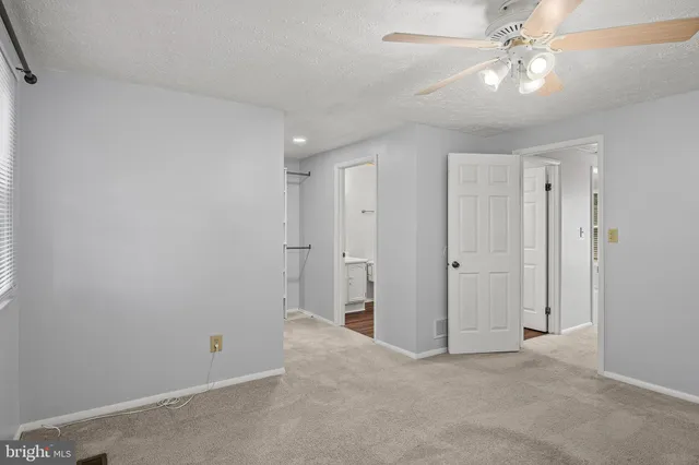 an empty room with a window and a fan