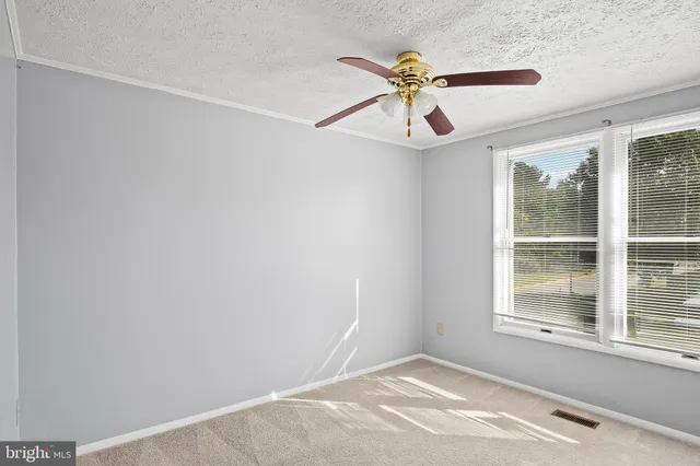 an empty room with windows and fan