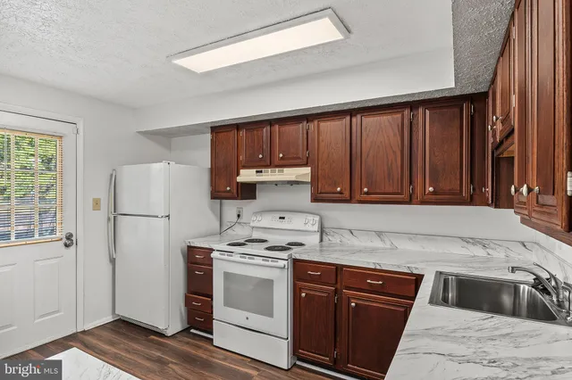 a kitchen with granite countertop a refrigerator stove and sink