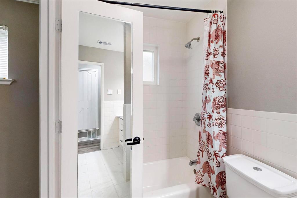 3264 Northaven Road Dallas, TX 75229 - Photo 23 of 35 Full bathroom with tile walls, shower / tub combo with curtain, toilet, and wainscoting