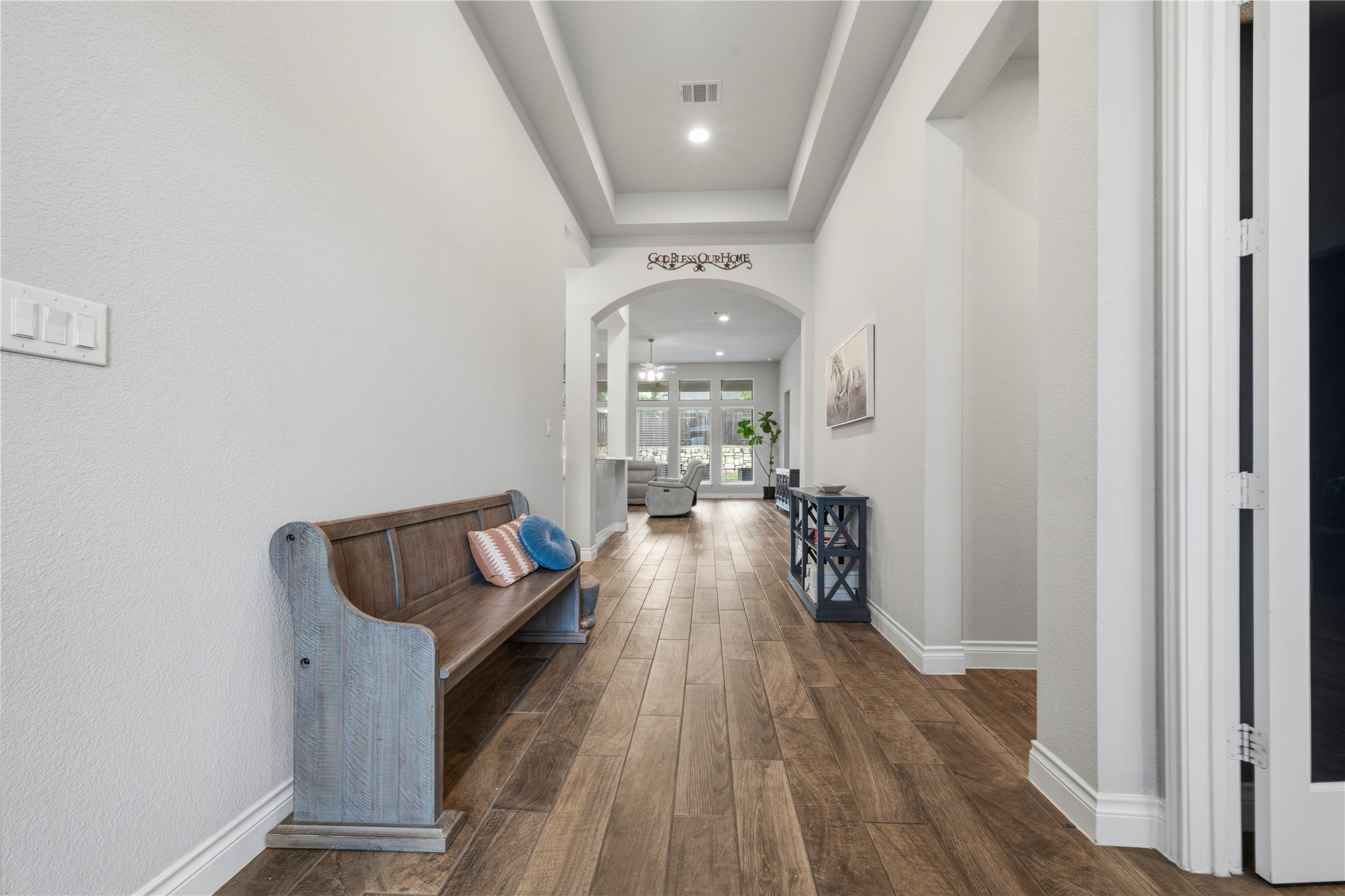 140 Catani Loop Georgetown, TX 78628 - Photo 3 of 36 Long hallway features warm wood flooring and recessed lighting, leading to an arched entryway.