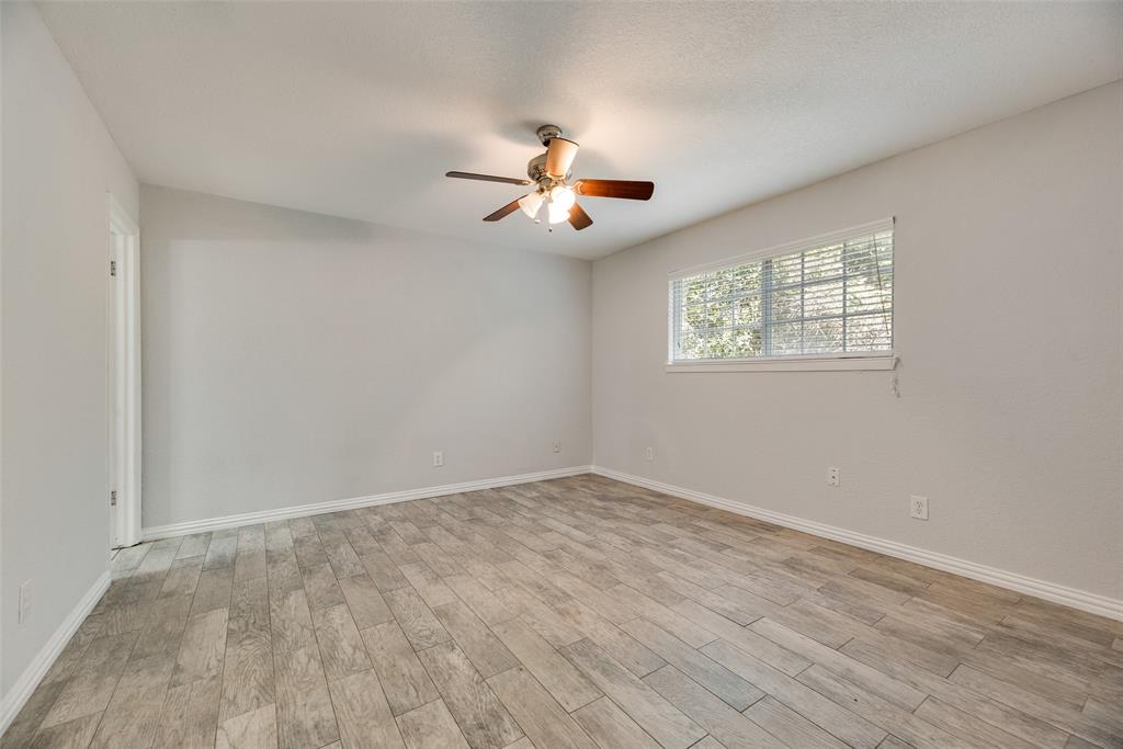 5109 Cedar Springs Road, Unit 105 Dallas, TX 75235 - Photo 11 of 16 Spacious room featuring wood-finish flooring, light grey wall paint, and a ceiling fan with integrated lighting
