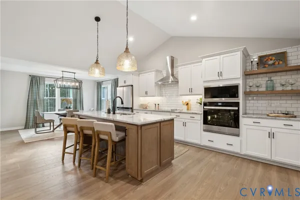 a kitchen with stainless steel appliances a stove center island a stove and a wooden floor