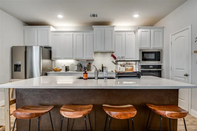 a kitchen with stainless steel appliances granite countertop a table chairs refrigerator and microwave