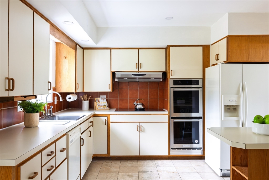 535 Clinton Road Brookline, MA 02467 - Photo 7 of 12 a kitchen with stainless steel appliances a sink and cabinets