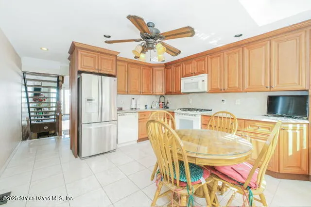 a kitchen with stainless steel appliances granite countertop a refrigerator a microwave a stove and white cabinets with wooden floor