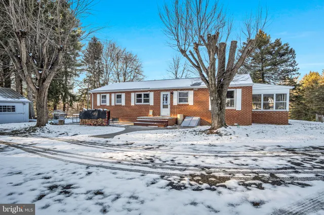 a front view of a house with a dirt yard and a large tree