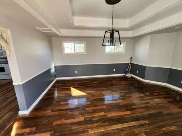 a view of wooden floor a chandelier and window in a room