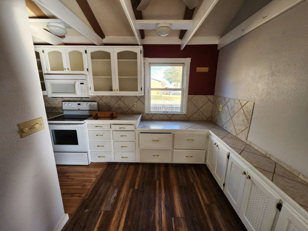 108 East 9th Street Channing, TX 79018 - Photo 9 of 16 a kitchen with stainless steel appliances a stove and white cabinets