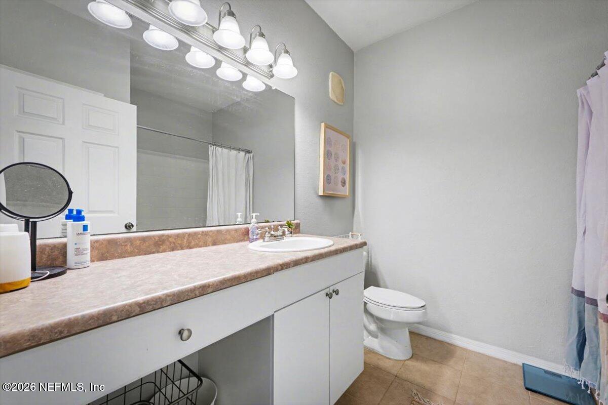 10961 Burnt Mill Road, Unit 1017 Jacksonville, FL 32256 - Photo 14 of 26 a bathroom with a granite countertop sink a toilet and a mirror