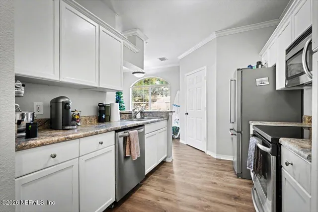 a kitchen with white cabinets and stainless steel appliances