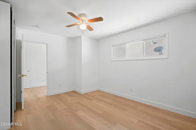 an empty room with a ceiling fan and wooden floor