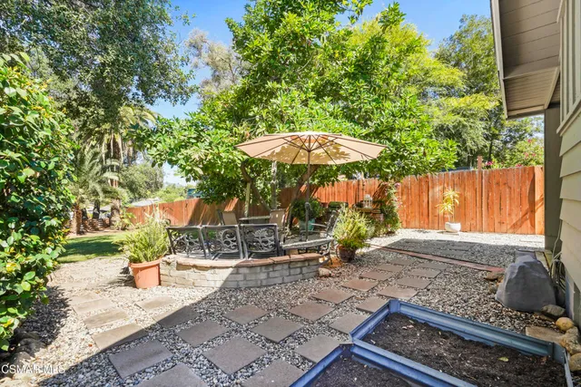 a backyard of a house with table and chairs under an umbrella
