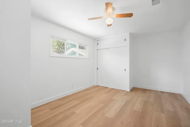 an empty room with a window and a fan