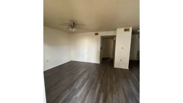 a view of a room with wooden floor and a ceiling fan