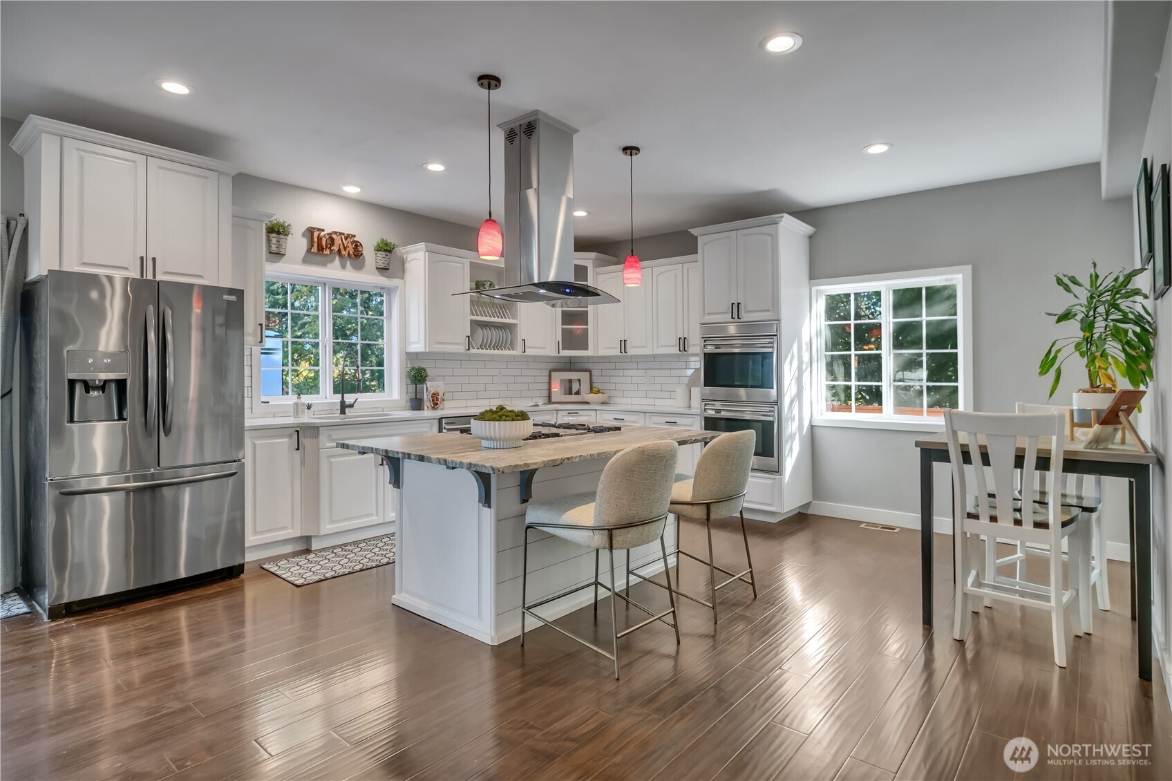 204 5th Avenue Milton, WA 98354 - Photo 12 of 37 a kitchen with stainless steel appliances kitchen island granite countertop a refrigerator a stove a sink a dining table and chairs with wooden floor