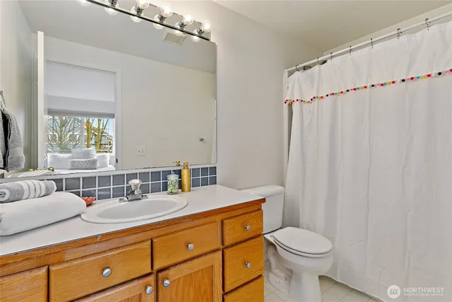 a bathroom with a granite countertop sink mirror vanity and toilet