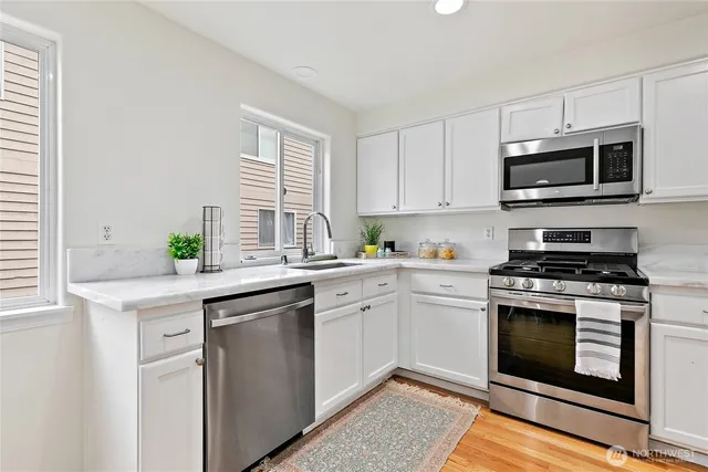 a kitchen with stainless steel appliances granite countertop a stove a sink and a microwave