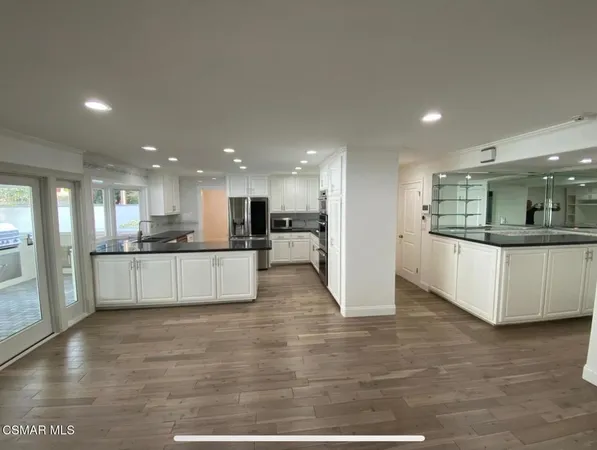 a view of kitchen with kitchen island white cabinets and stainless steel appliances