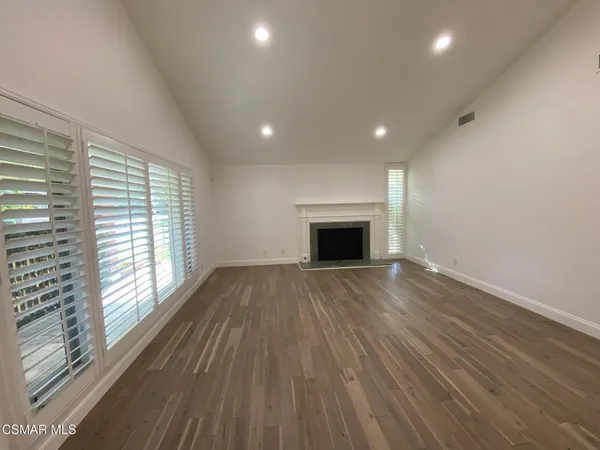 a view of empty room with wooden floor and fireplace