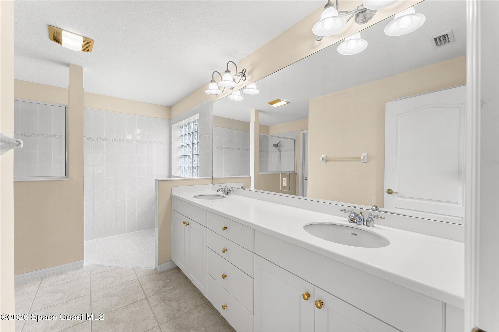 6904 Renshaw Drive Melbourne, FL 32940 - Photo 22 of 46 a bathroom with a double vanity sink a mirror and a shower