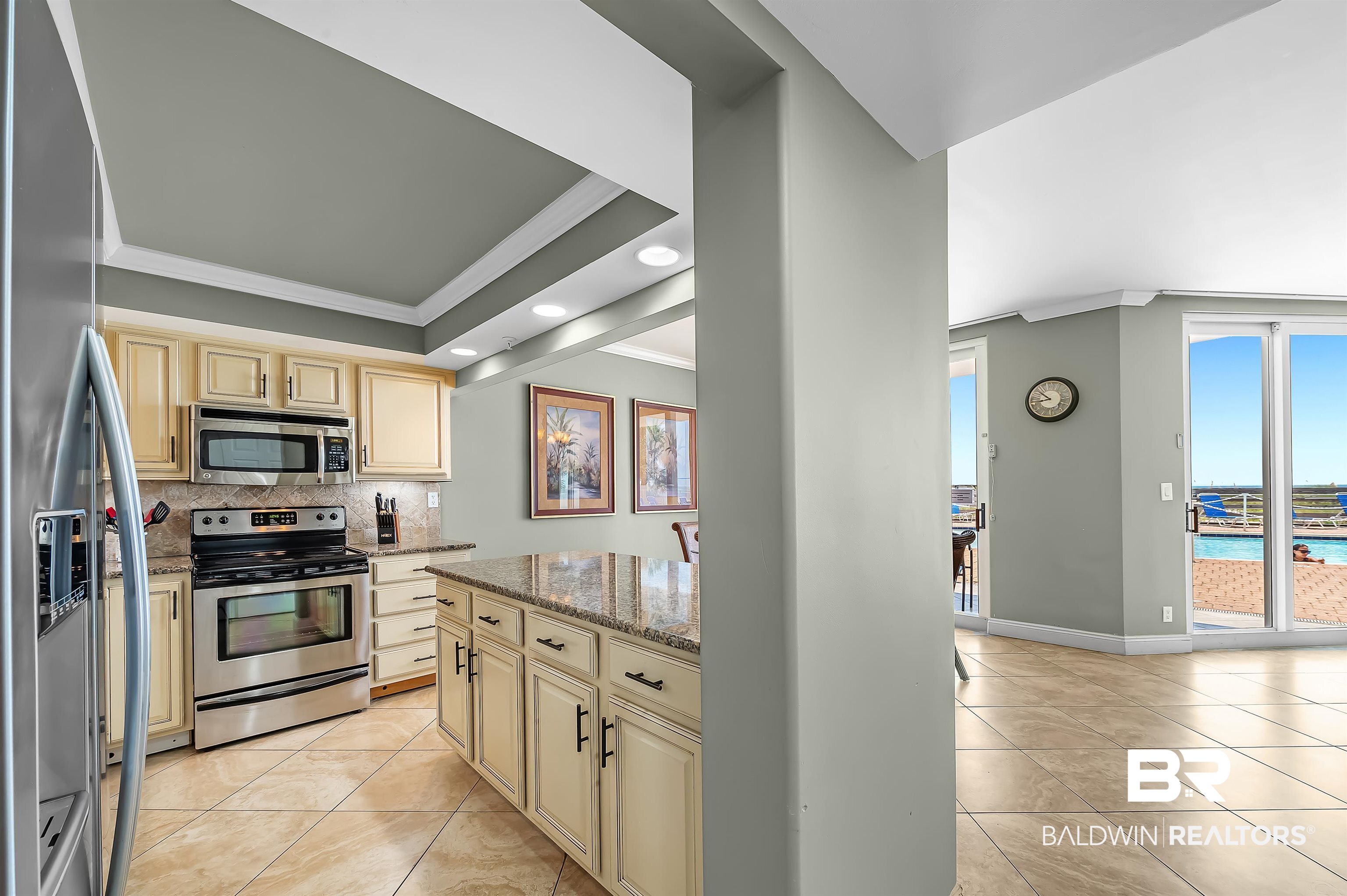 16287 Perdido Key Drive, Unit 105 Pensacola, FL 32507 - Photo 22 of 66 Kitchen featuring a large island with stone countertop, stainless steel appliances, tile flooring, and cream-colored cabinetry