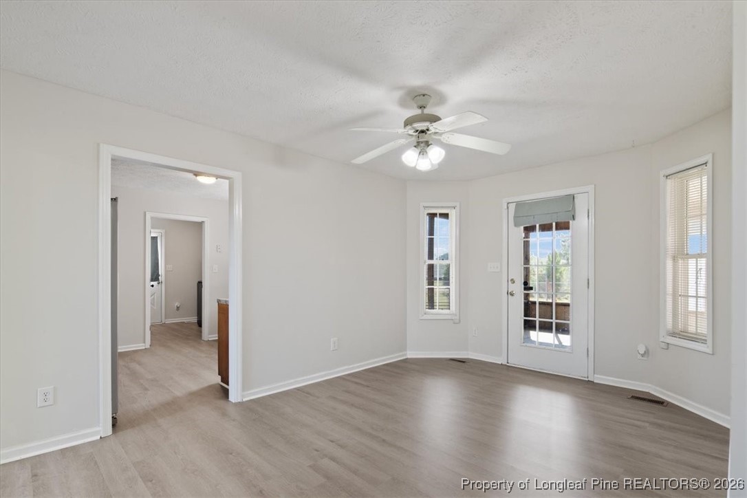 151 Ballard Drive Raeford, NC 28376 - Photo 18 of 34 an empty room with wooden floor ceiling fan and windows