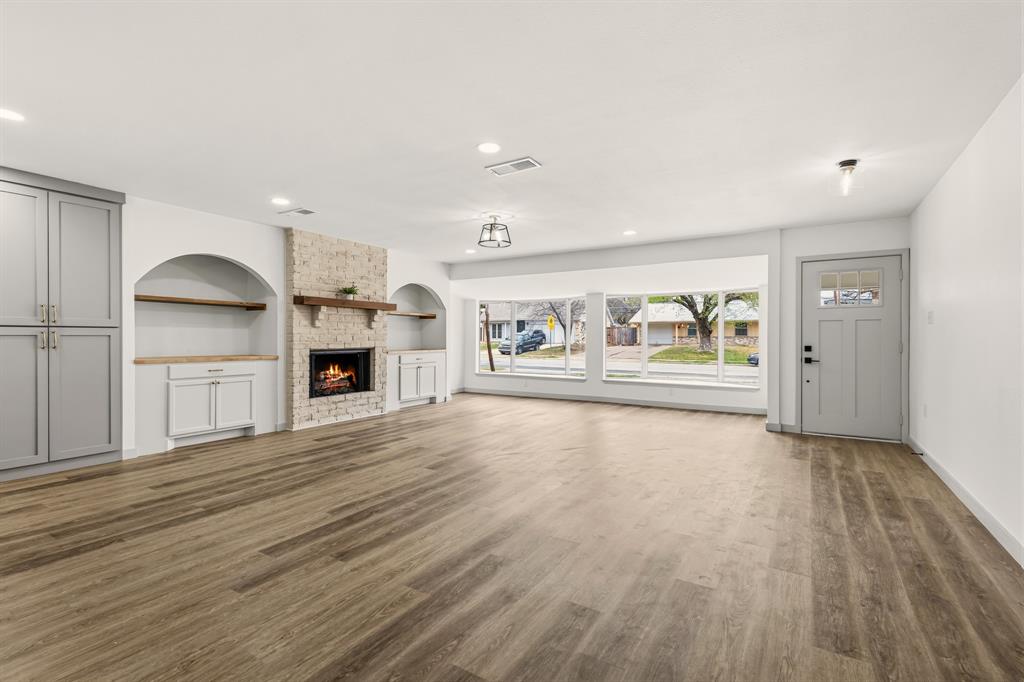 1510 Finley Road Irving, TX 75062 - Photo 3 of 17 an empty room with wooden floor fireplace and windows