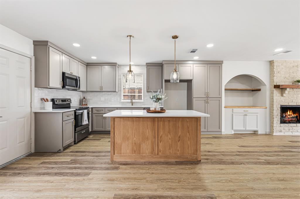 1510 Finley Road Irving, TX 75062 - Photo 5 of 17 a large kitchen with stainless steel appliances kitchen island granite countertop a stove a sink a refrigerator and a wooden floors