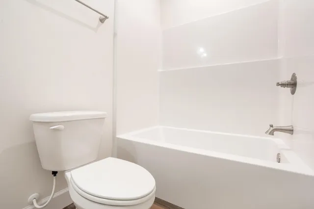 a white toilet sitting next to a bath tub
