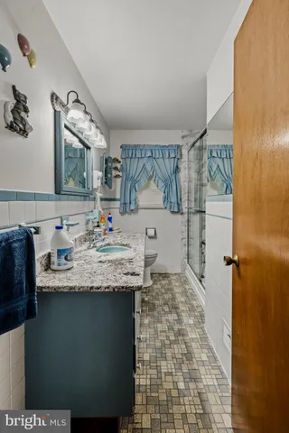a bathroom with a granite countertop sink a toilet and shower