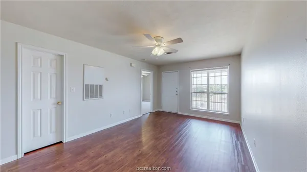 a view of an empty room with a window and wooden floor