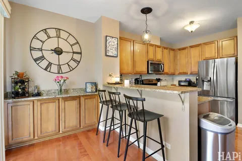 a kitchen with stainless steel appliances granite countertop a stove a sink dishwasher and a refrigerator with wooden floor