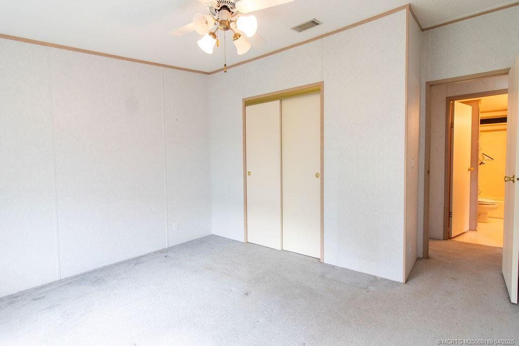 2500 Southwest Marquis Terrace Stuart, FL 34997 - Photo 13 of 20 an empty room with a chandelier fan and windows