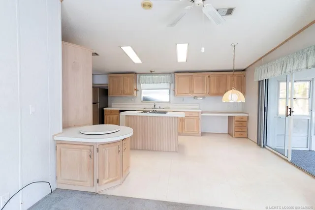 a large kitchen with kitchen island a sink a stove a refrigerator and white cabinets with wooden floor