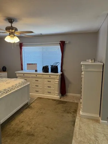 a bed sitting in a bedroom and dressers next to a window