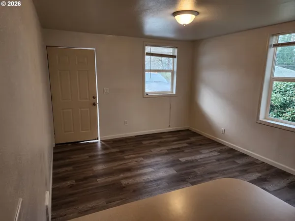 an empty room with wooden floor and windows