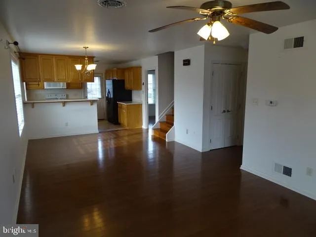 a kitchen with stainless steel appliances granite countertop a refrigerator a stove a sink and dishwasher with wooden floor