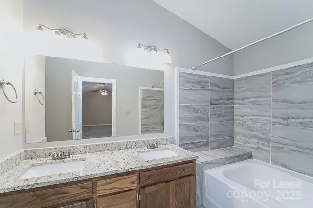 a bathroom with a granite countertop sink mirror and a bath tub