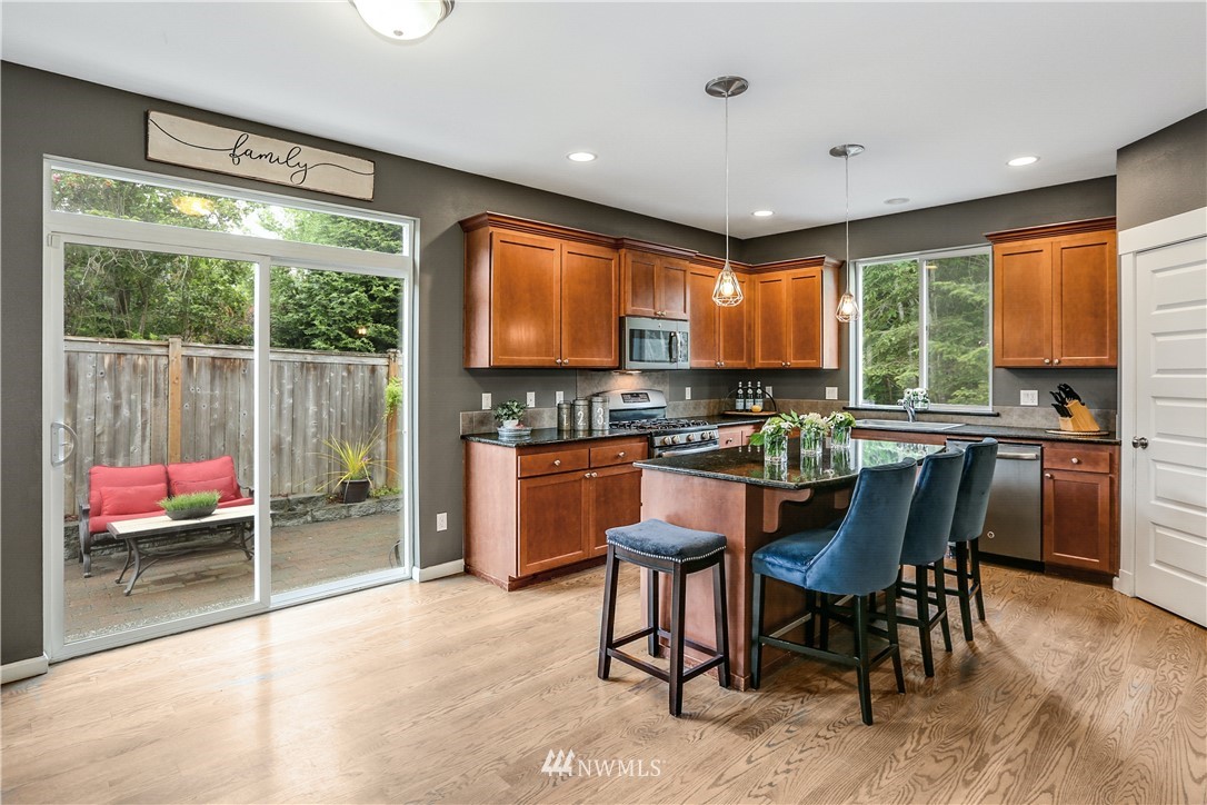22505 38th Avenue Southeast Bothell, WA 98021 - Photo 11 of 39 a kitchen with stainless steel appliances kitchen island granite countertop a stove a refrigerator a sink a dining table and chairs with wooden floor