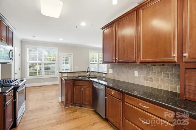 a kitchen with stainless steel appliances granite countertop wooden cabinets and a stove top oven