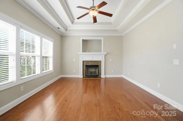 a view of an empty room with wooden floor fireplace and a window