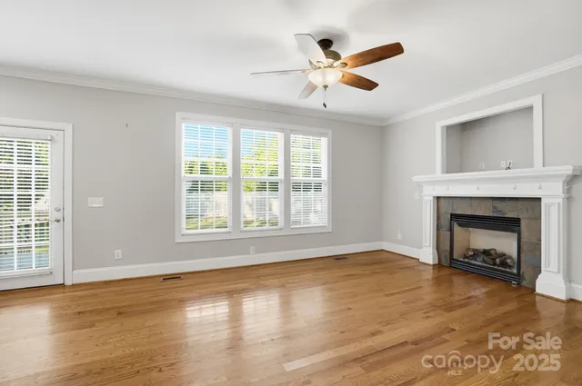a view of empty room with wooden floor and a fireplace