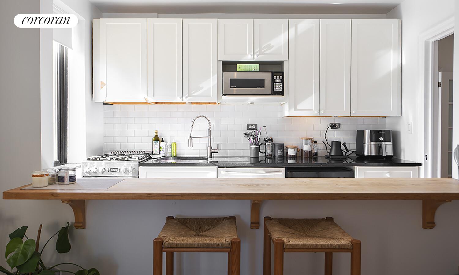 255 West 23rd Street, Unit 5FW Manhattan, NY 10011 - Photo 2 of 8 a kitchen with stainless steel appliances granite countertop a sink a stove and microwave