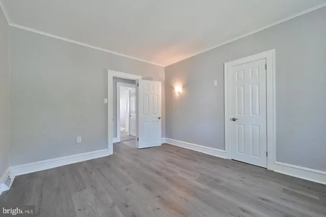 a view of an empty room with wooden floor and closet