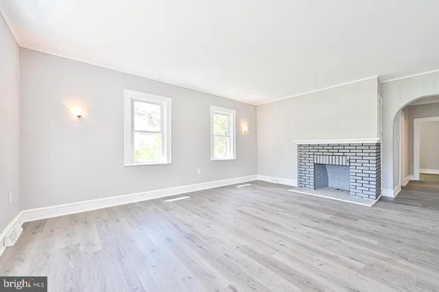 an empty room with wooden floor fireplace and windows
