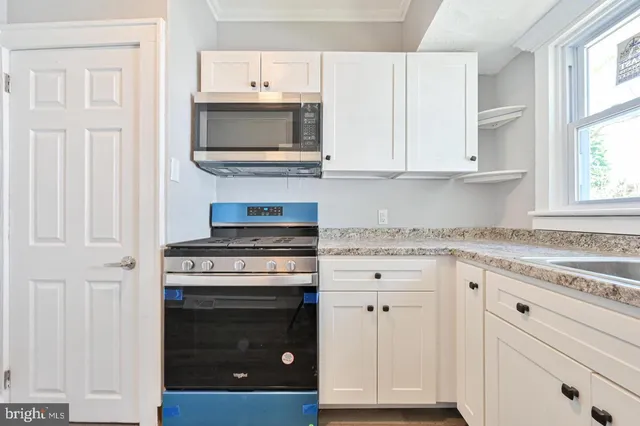 a kitchen with granite countertop white cabinets and appliances