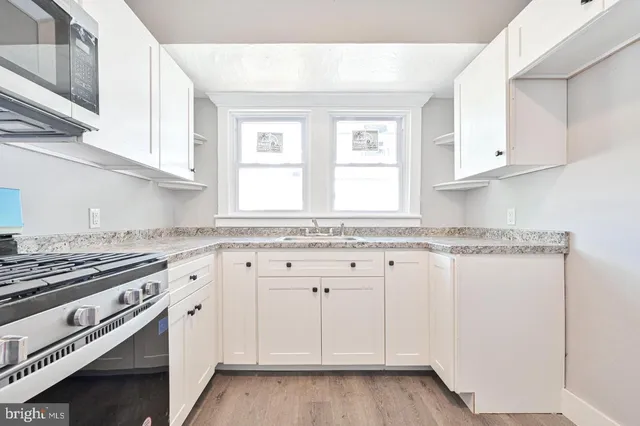 a kitchen with granite countertop white cabinets and white appliances