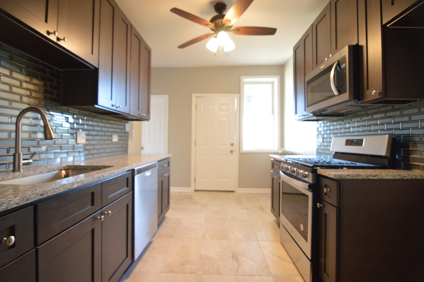 3422 West Grenshaw Street, Unit 2 Chicago, IL 60624 - Photo 10 of 12 a kitchen with stainless steel appliances granite countertop a sink a stove top oven a refrigerator with wooden cabinets and floor