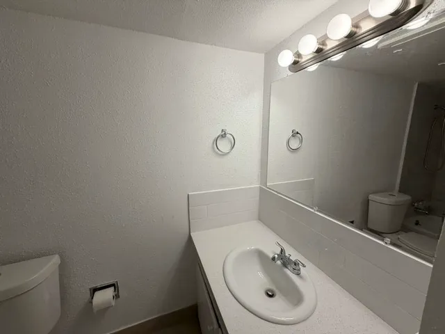 a bathroom with a granite countertop sink a toilet and a mirror